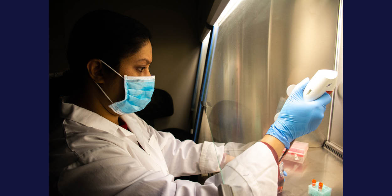 Une femme avec un masque et des gants dans un laboratoire qui mène des expériences