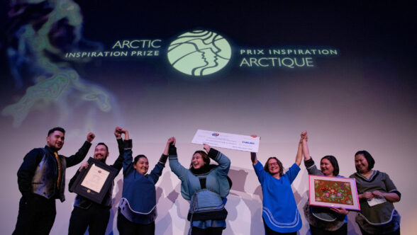 Laureates celebrate their win on stage with a giant cheque.