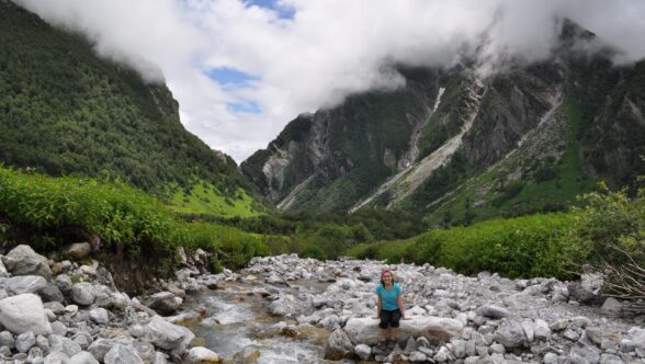 A woman sitting on rocks in a valley between two mountains