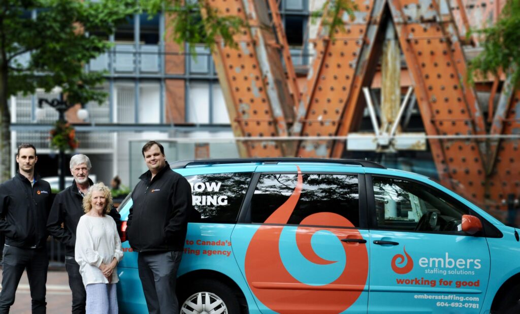 4 people posing outside with customized embers van
