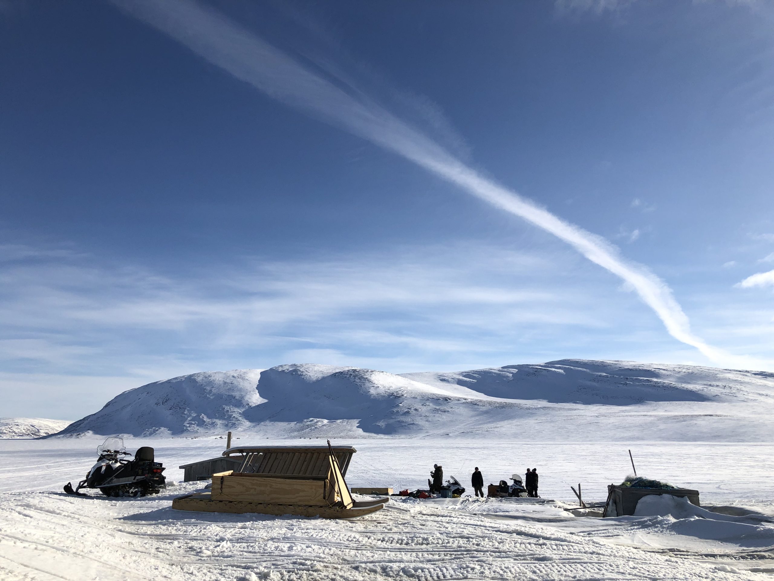 outdoor arctic camp set up with people and snow mobile