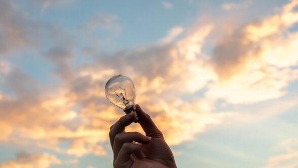 hand holding light bulb up to the sky