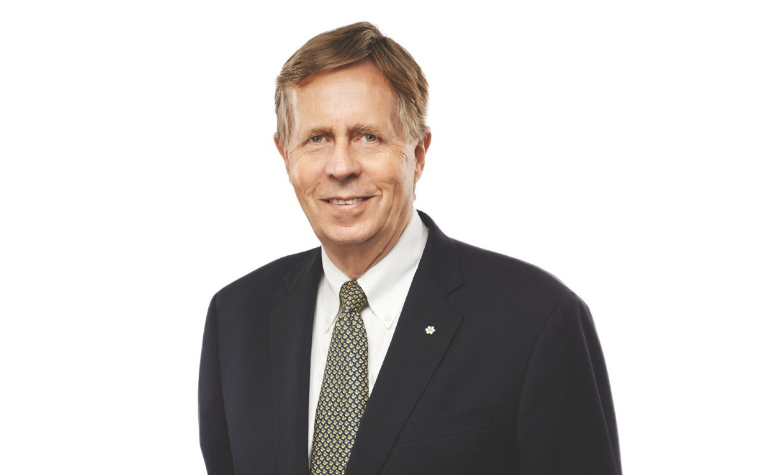 A man in a dark suit and patterned tie smiles at the camera.